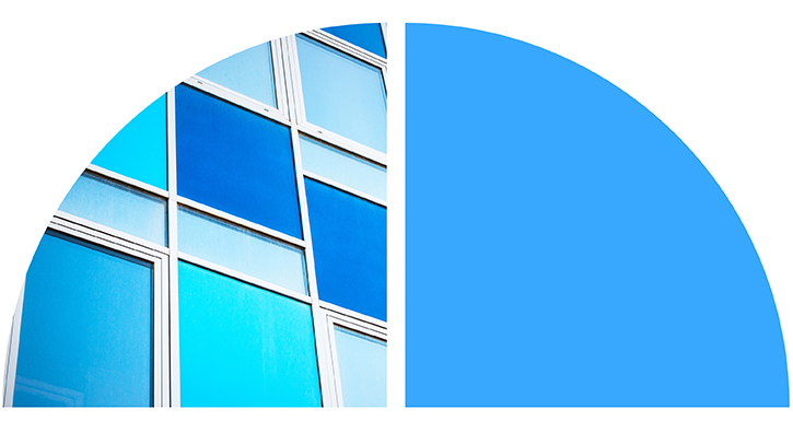 Abstract blue-toned glass building facade with geometric panes and curved shapes.